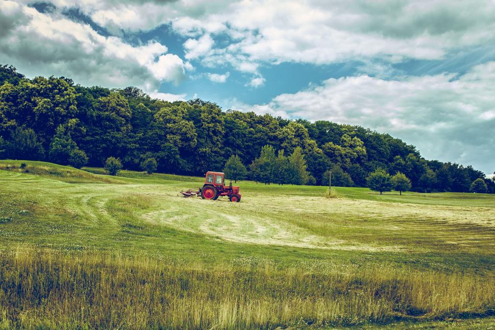 Free Image of A Tractor Driving Through a Grassy Field 