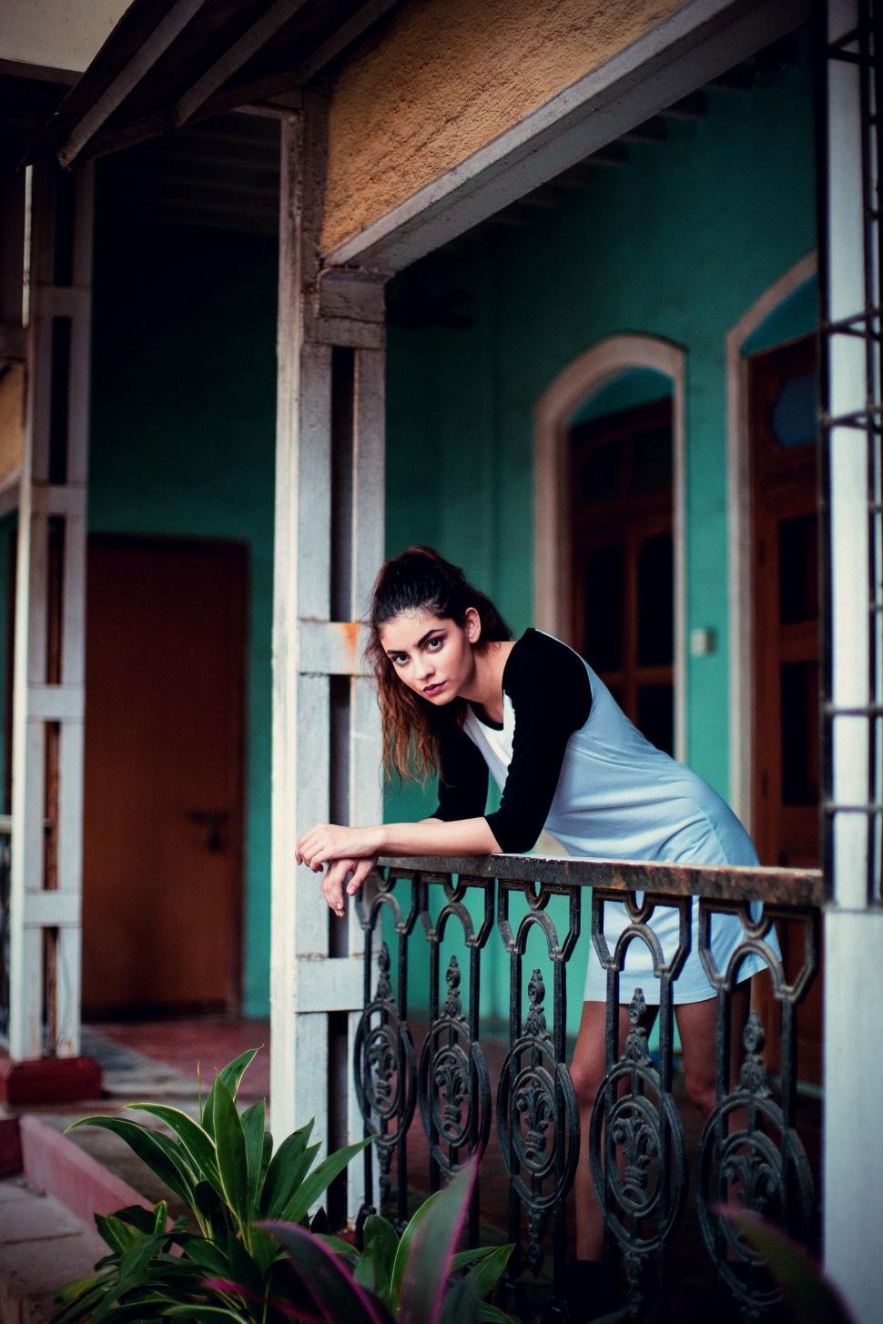 Free Image of Woman Leaning on Railing in Front of Building 