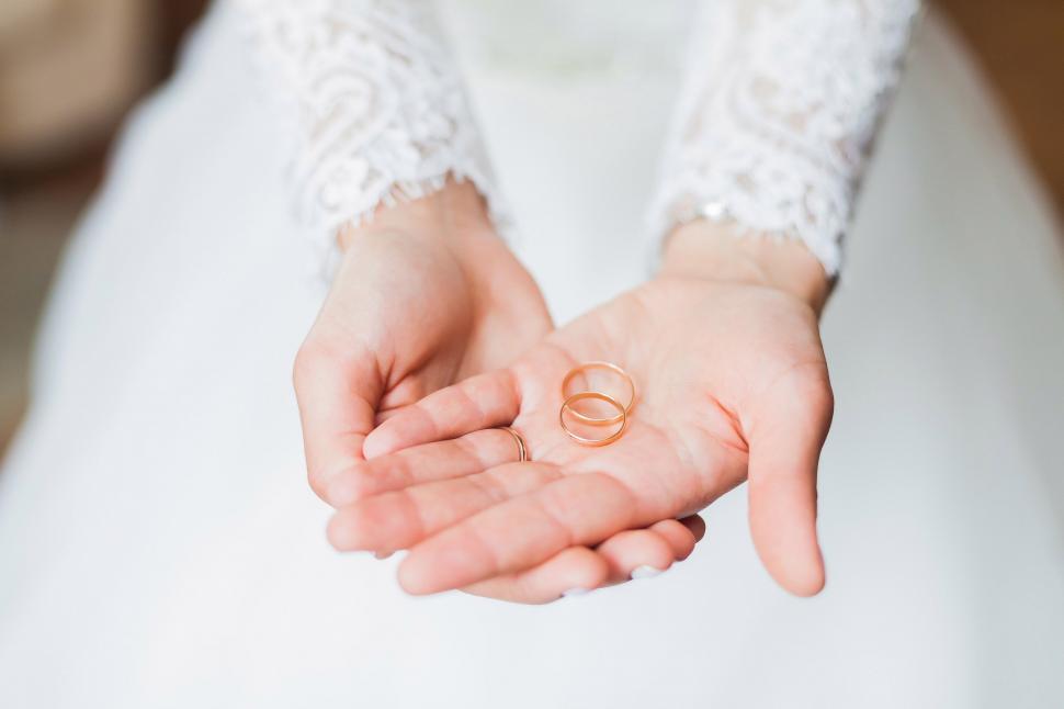 Free Image of Woman in White Dress Holding Wedding Ring 