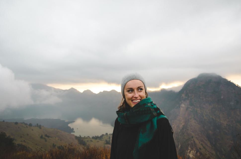 Free Image of Woman Standing on Top of a Mountain Under Cloudy Sky 