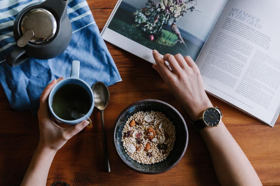 Free Image of Person Sitting at Table With Book and Bowl of Cereal 