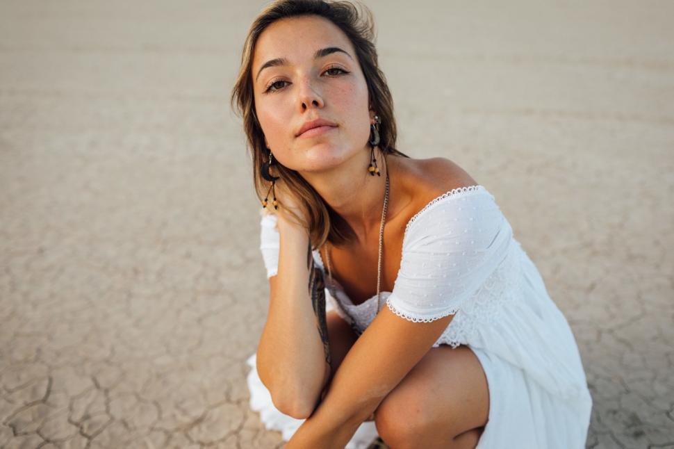 Free Image of Woman in a White Dress Sitting on the Ground 