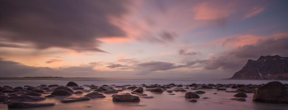 Free Image of Rocky Beach Covered in Rocks Under Cloudy Sky 