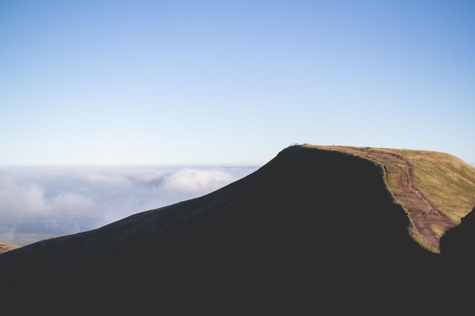 Free Image of Person Standing on Top of a Mountain With Sky Background 