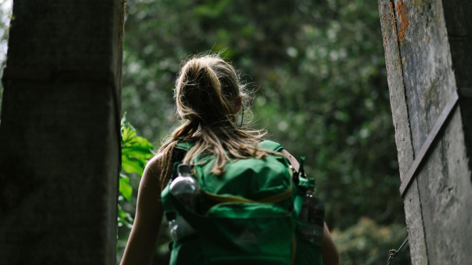 Free Image of Woman With Green Backpack Walking Through Forest 