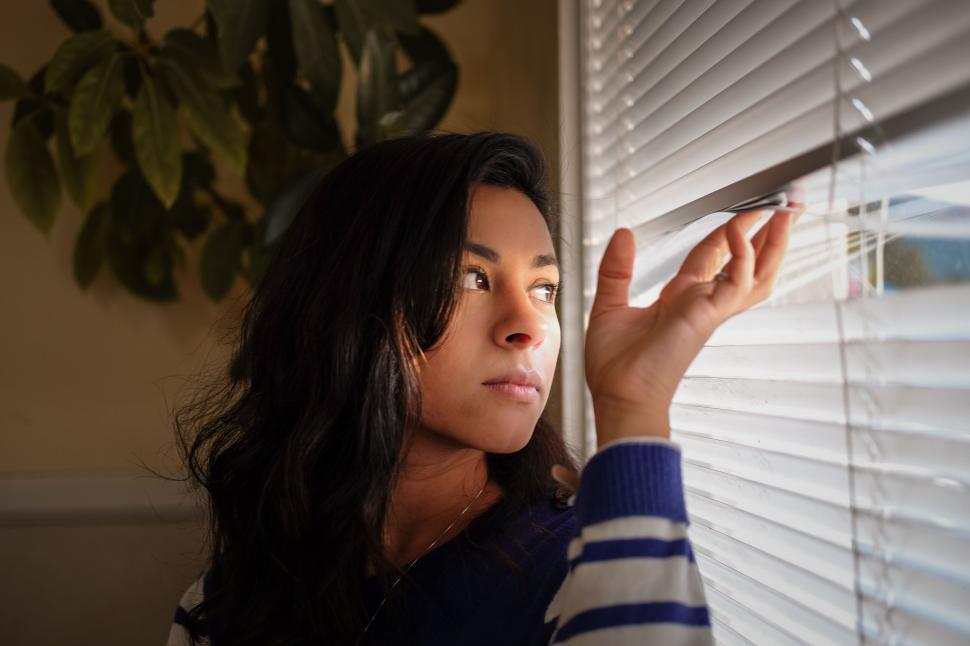 Free Image of Woman Looking Out of Window With Blinds 