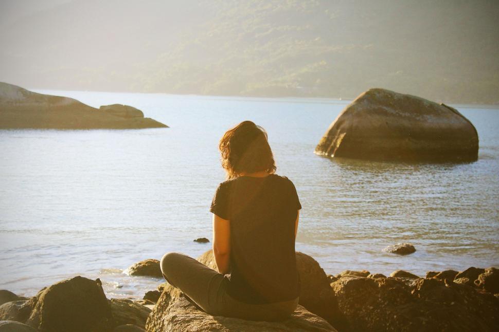 Free Image of Person Sitting on Rock Near Water 