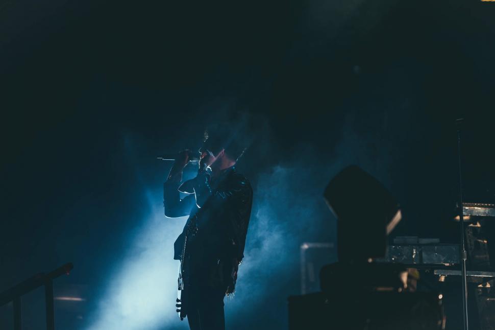 Free Image of Man Standing on Stage Holding Microphone 