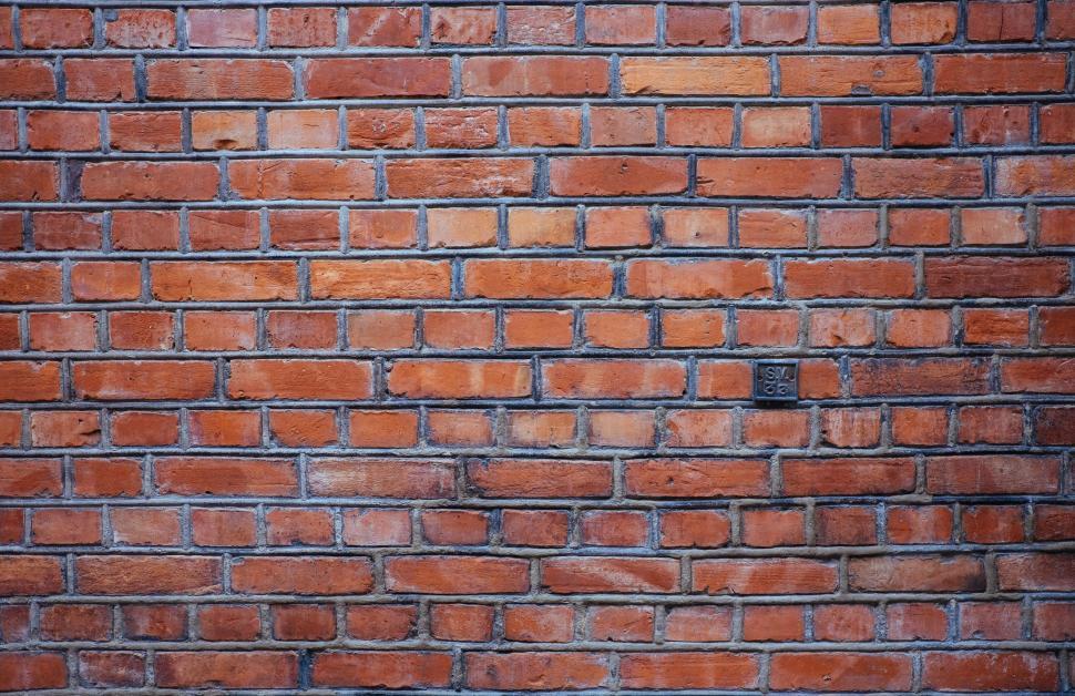 Free Image of Red Brick Wall With Black Square Sign 