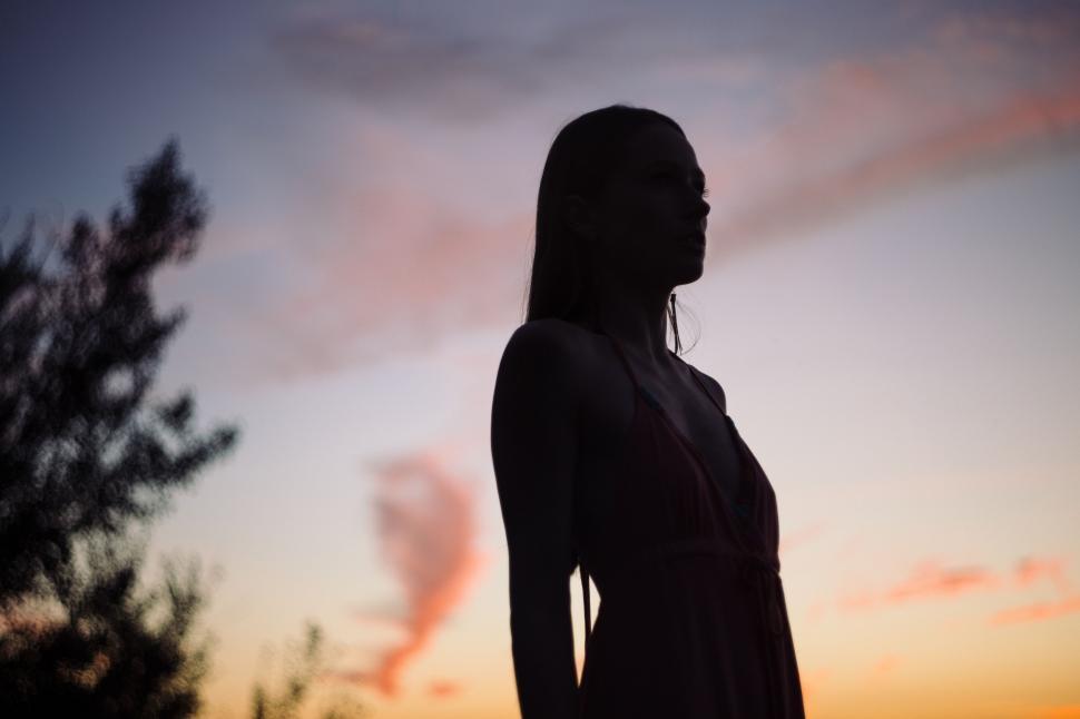 Free Image of Woman Silhouette Standing in Front of Sunset 