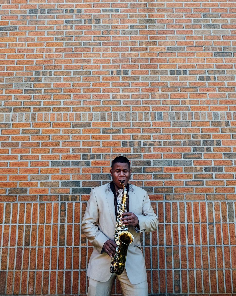 Free Image of Man Playing Saxophone in Front of Brick Wall 