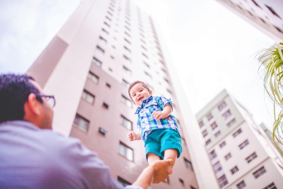 Free Image of Man Holding Small Child in Front of Tall Building 