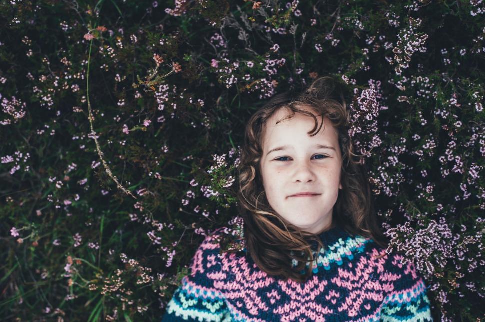 Free Image of Young Girl Laying in Grass Wearing Sweater 