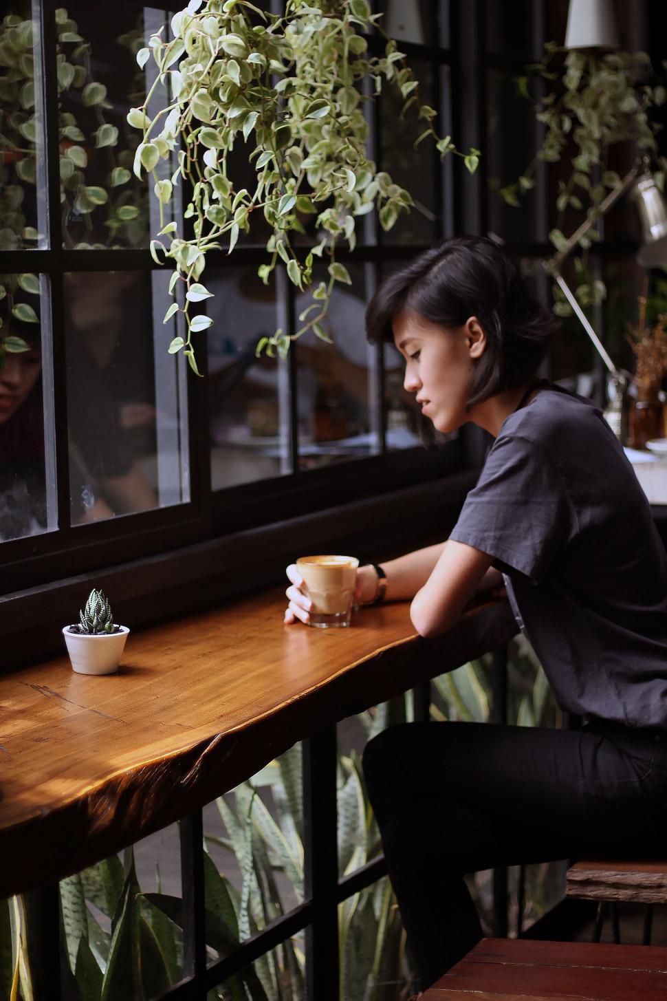 Free Image of Woman Sitting at Table With Coffee Cup 