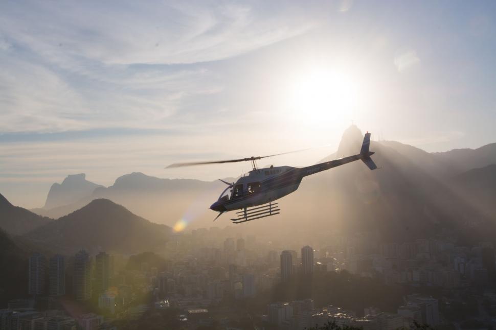 Free Image of Helicopter Flying Over City With Mountains in Background 