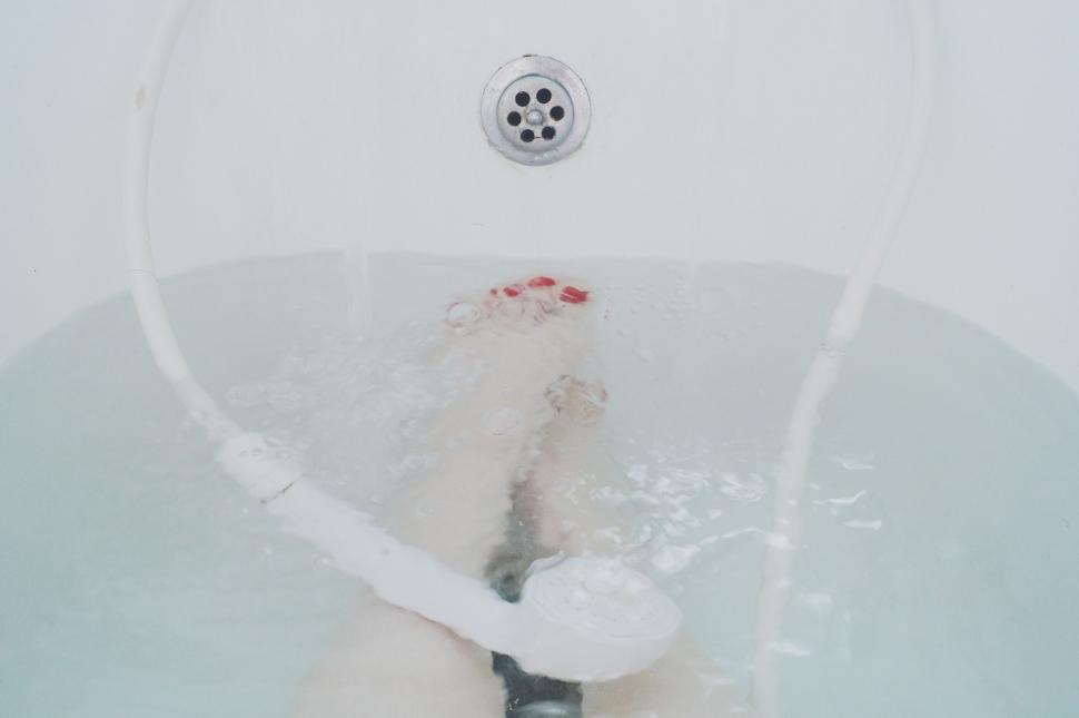 Free Image of Person Standing in Bathtub With Feet in Water 