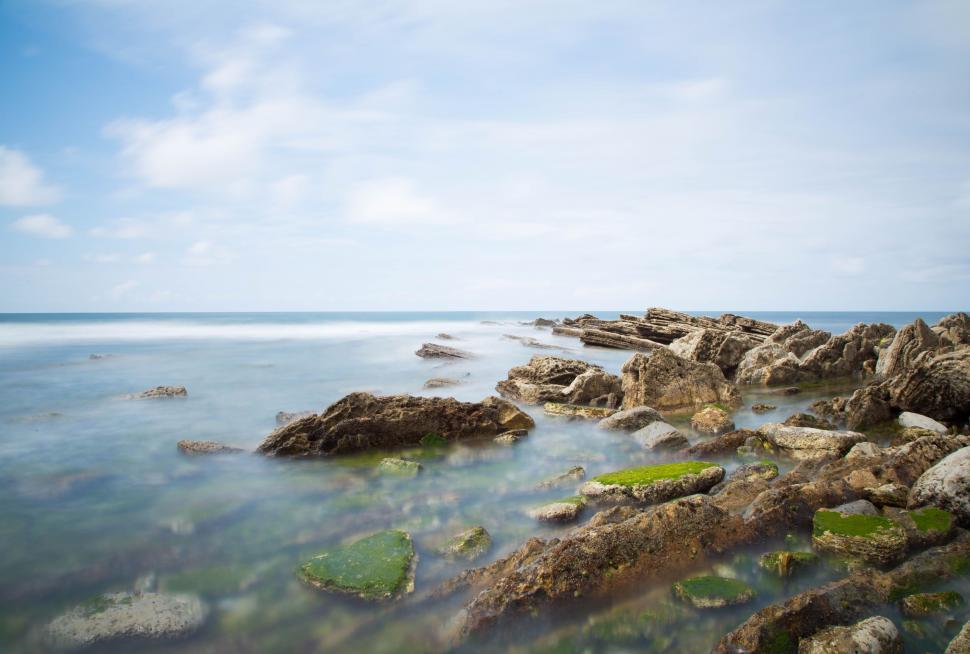 Free Image of Rocky Shoreline Surrounding Expansive Body of Water 
