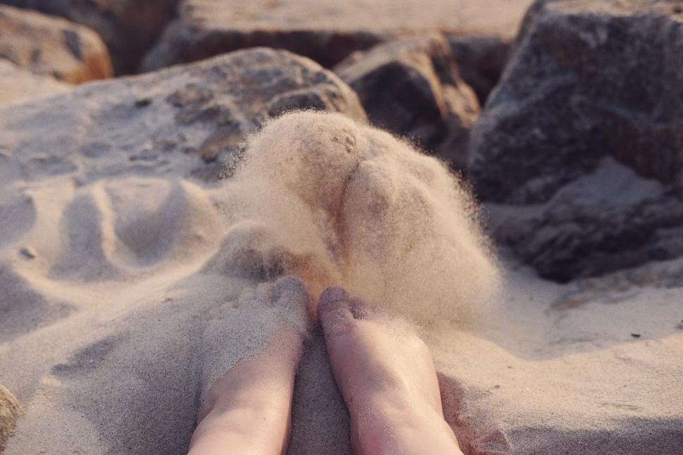 Free Image of Person Laying in Sand With Feet Buried 