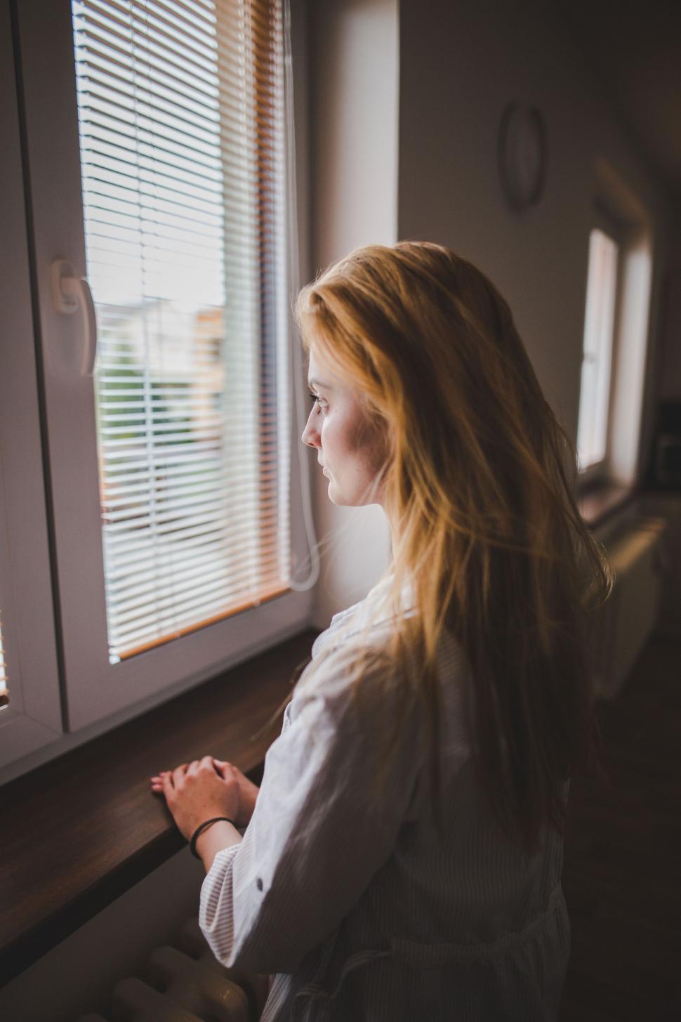 Free Image of Woman Looking Out a Window at the Outside 