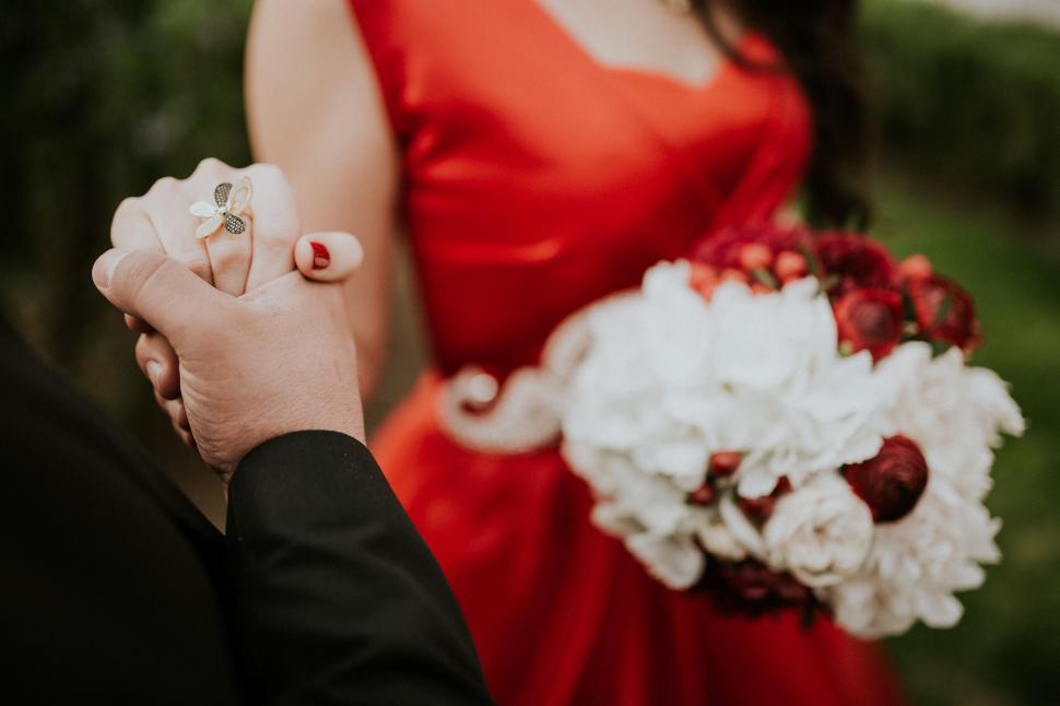 Free Image of Man and Woman Holding Hands With Bouquet of Flowers 