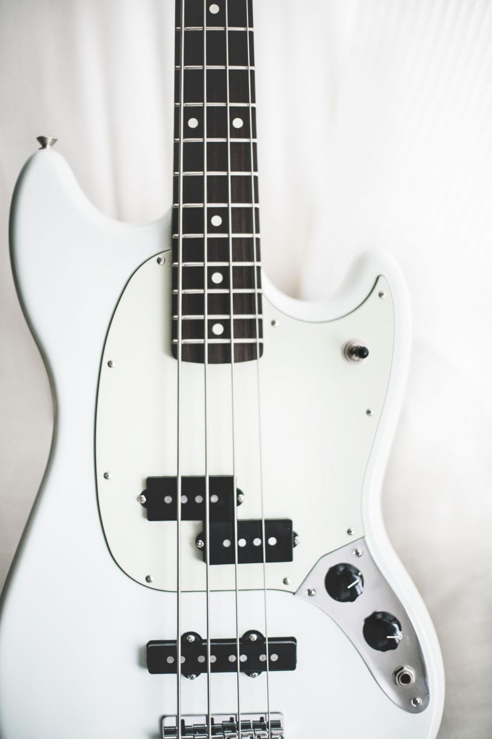 Free Image of White Bass Guitar on White Sheet 