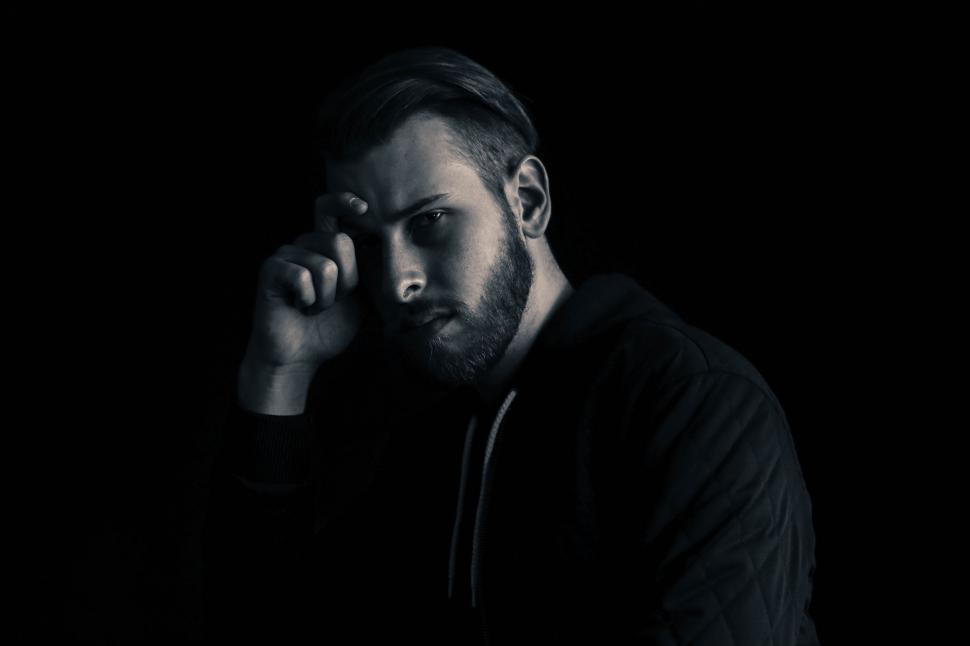Free Image of Man Sitting in the Dark With Hand on Head 
