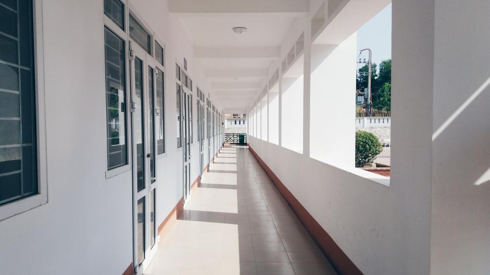 Free Image of Long Hallway With White Walls and Windows 