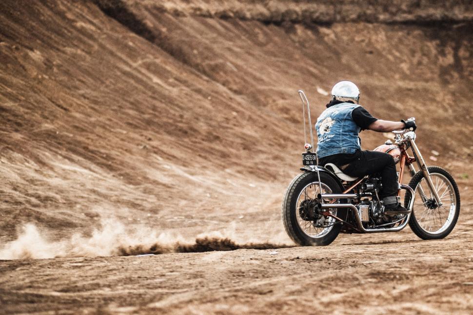 Free Image of Man Riding Motorcycle Down Dirt Road 