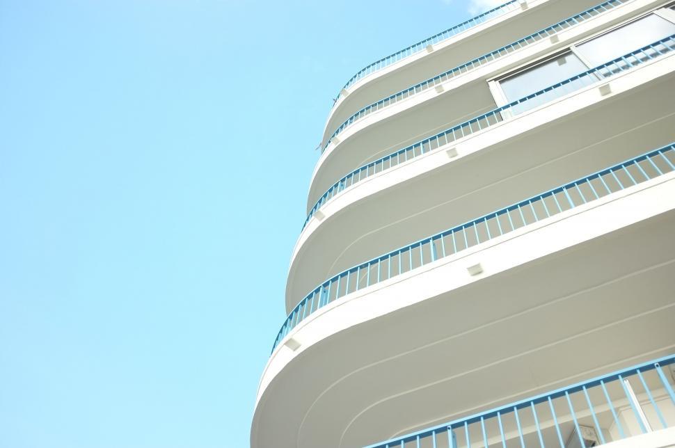 Free Image of Tall White Building With Balconies Against Blue Sky 