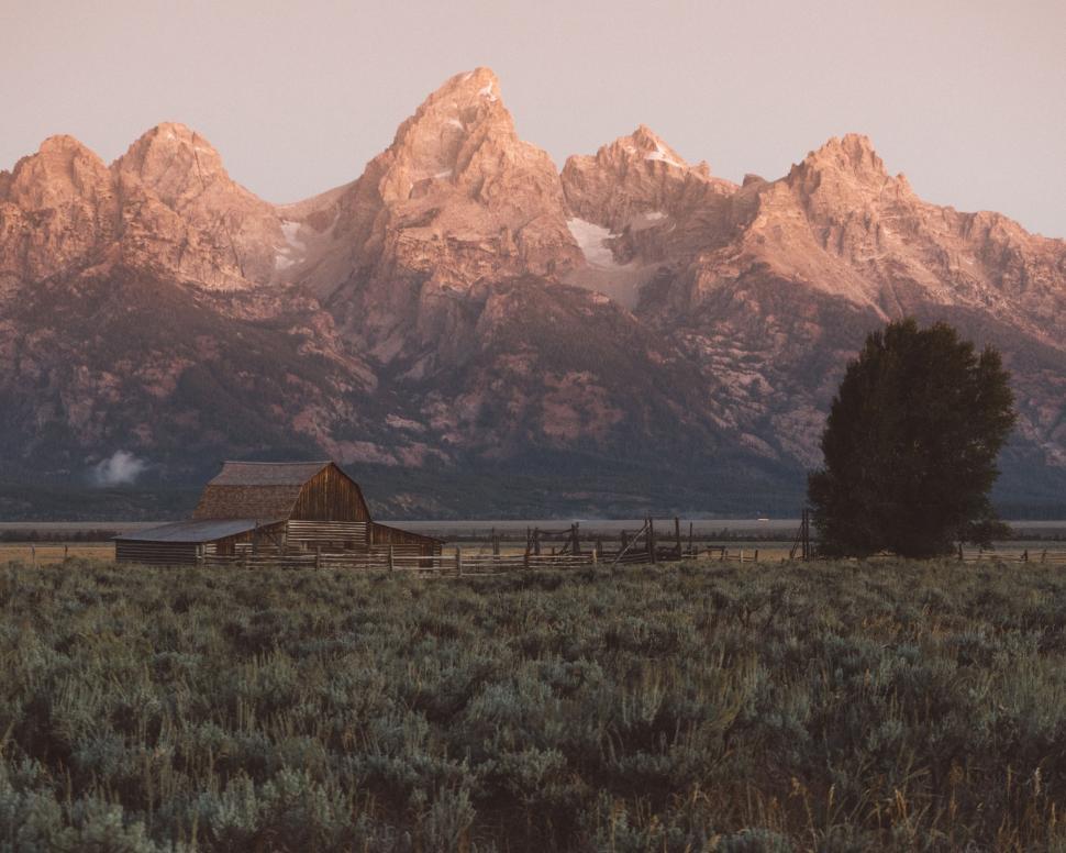 Free Image of Barn Standing in Field With Mountains 