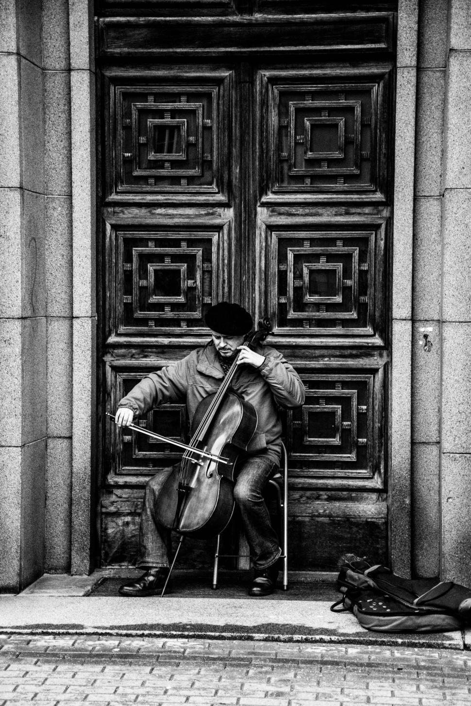 Free Image of Man Playing Cello in Front of Door 