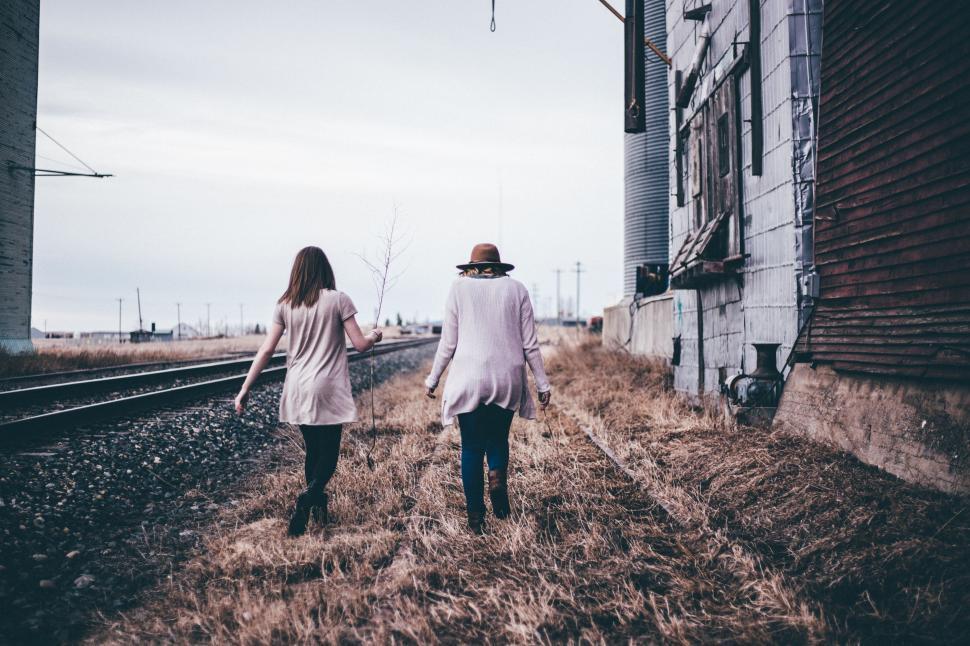 Free Image of Man and Woman Walking Down Train Track 