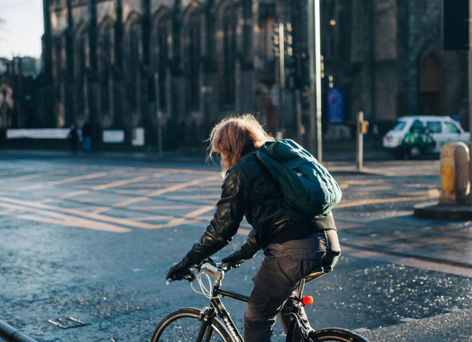 Free Image of Man Riding Bike Down Rain-Soaked Street 