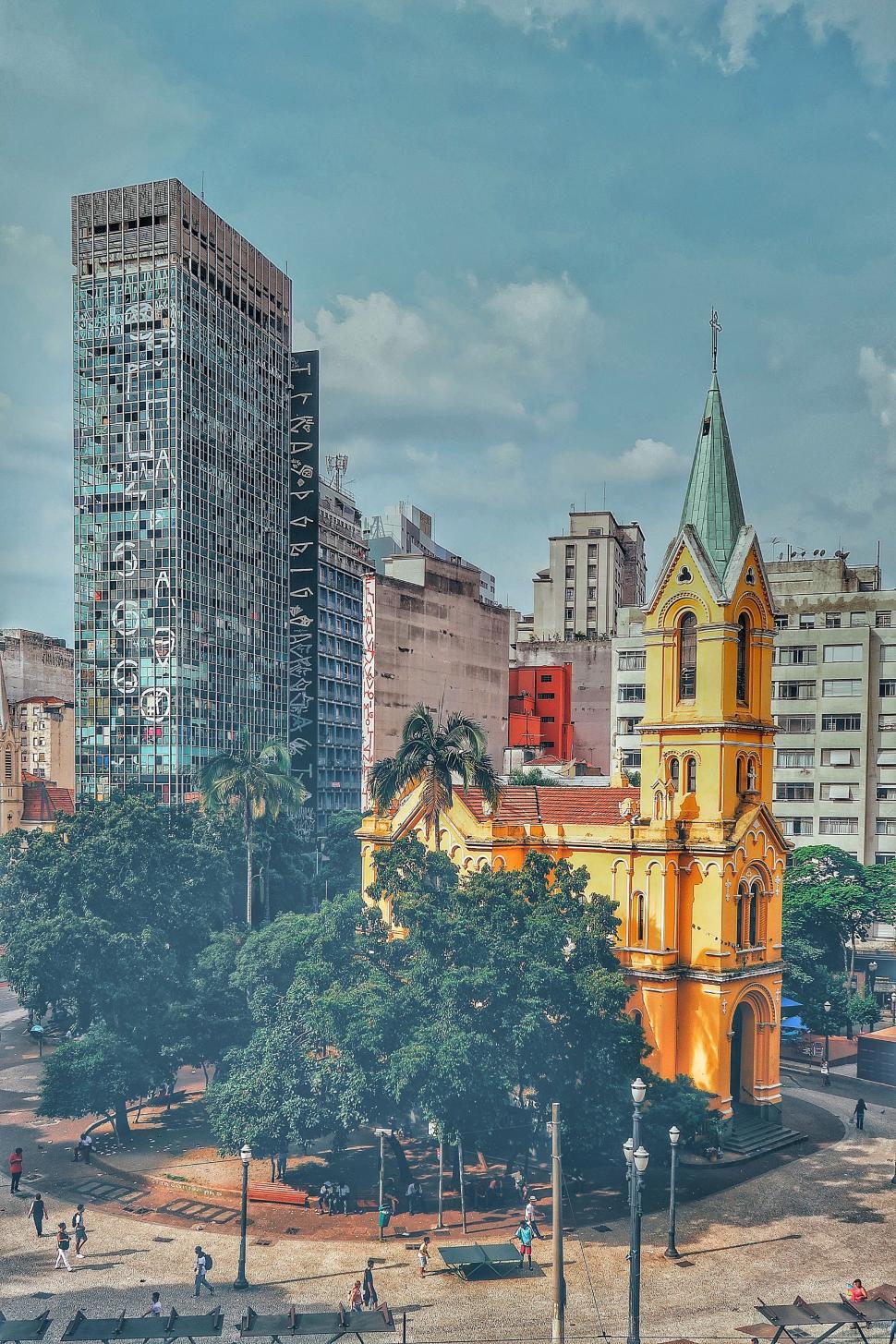 Free Image of Large Yellow Church Among Tall City Buildings 