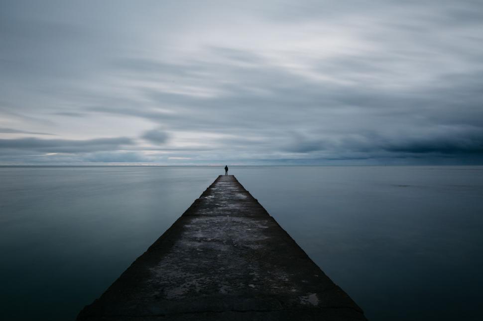 Free Image of Person Standing on Pier in Middle of Body of Water 
