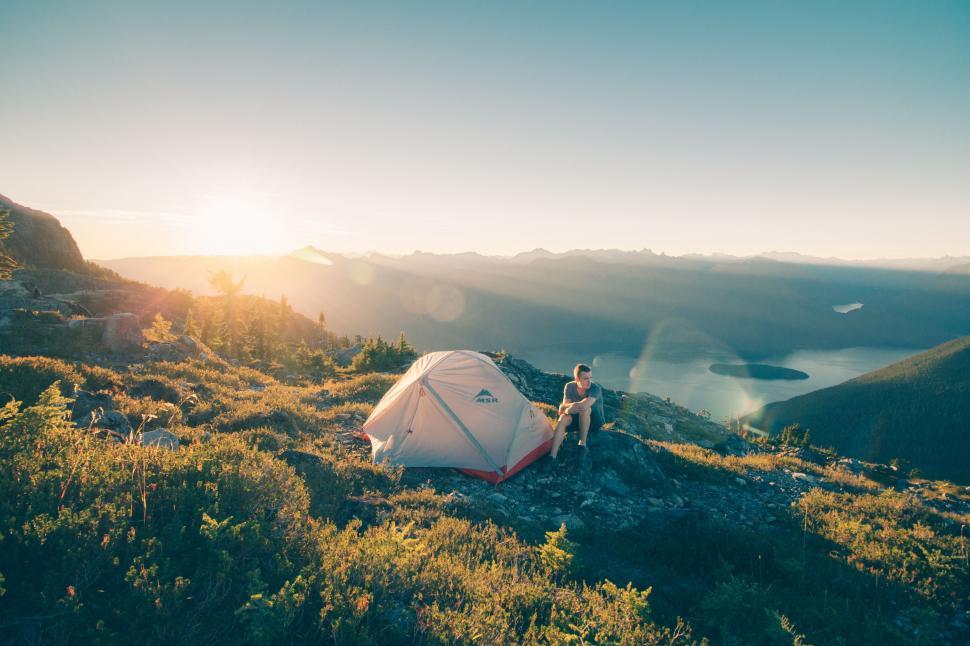 Free Image of Person Sitting Next to Tent on Mountain Top 