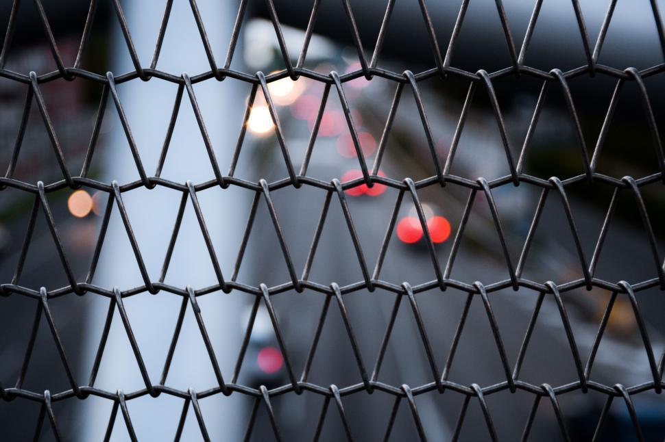 Free Image of Close-up of Fence With Cars in Background 