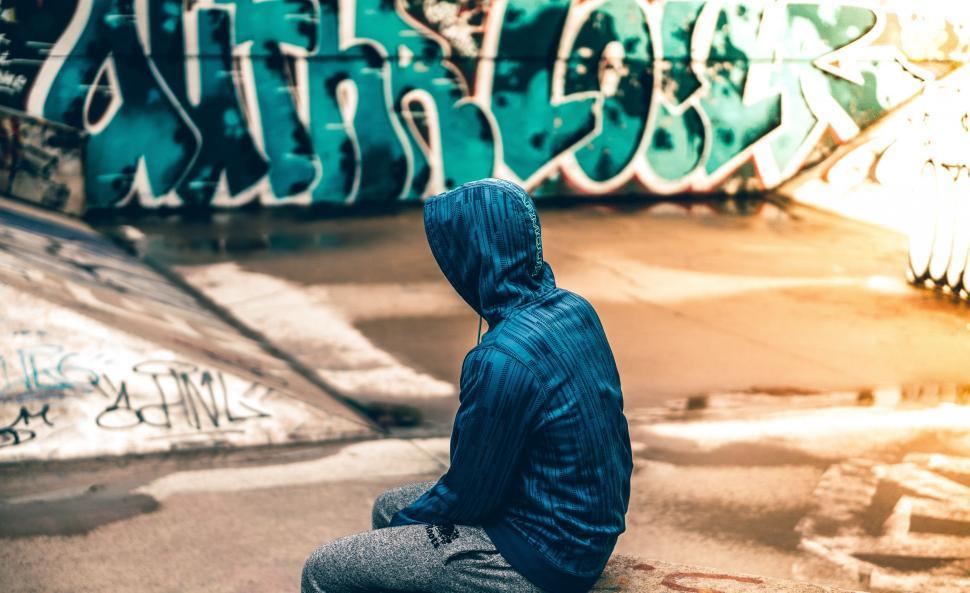 Free Image of Person Sitting in Front of Graffiti Covered Wall 
