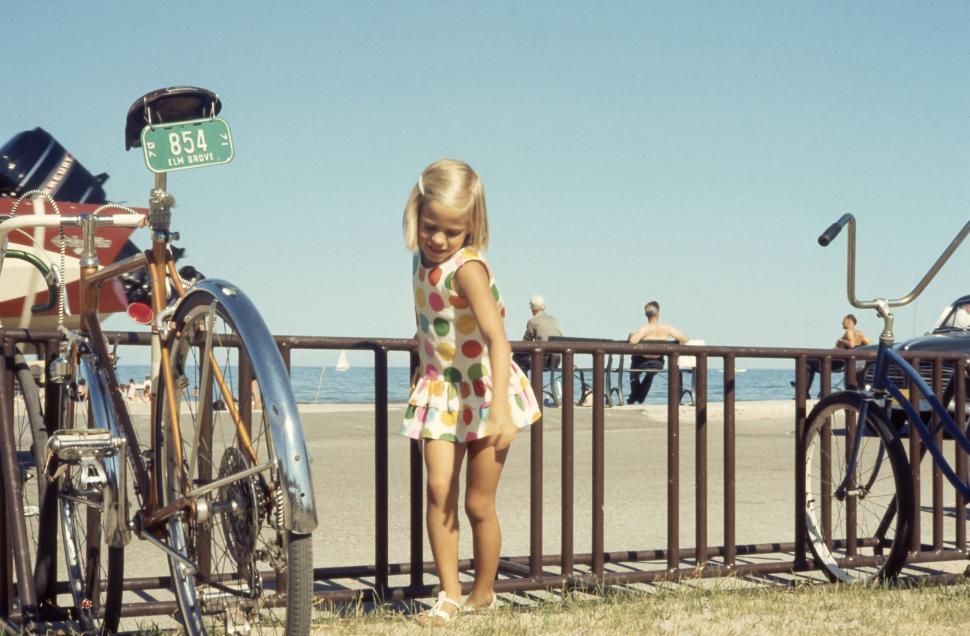 Free Image of Little Girl Standing Next to Bicycles 