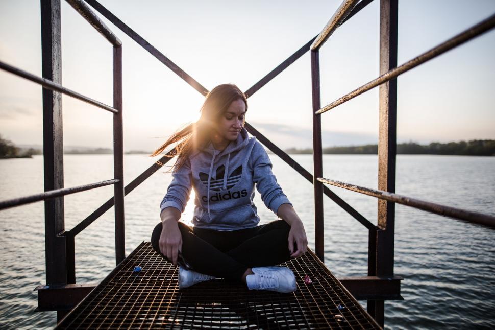 Free Image of Woman Sitting on Dock by Water 