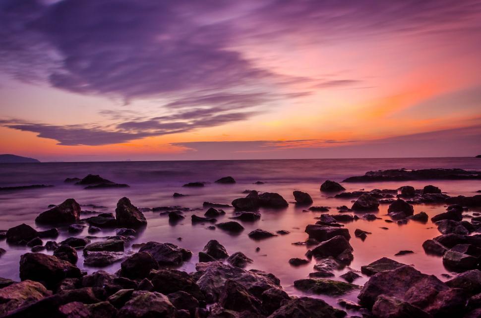 Free Image of A Rocky Beach at Sunset With a Purple Sky 