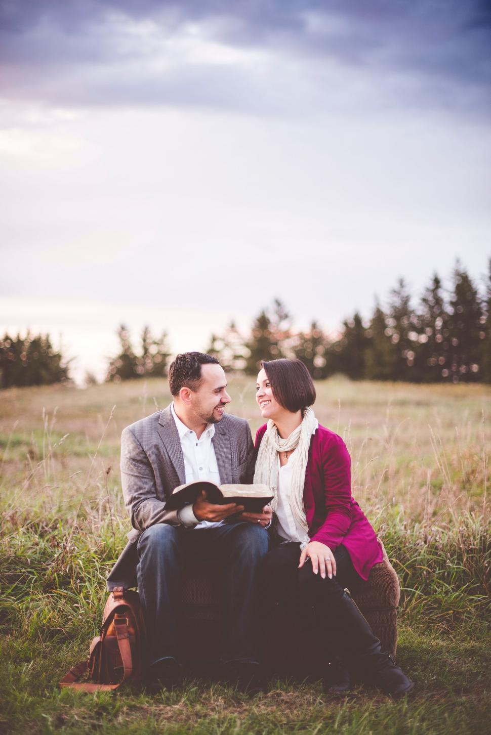 Free Image of Man and Woman Sitting in Field With Book 