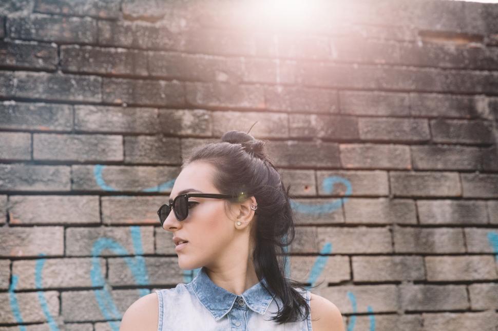 Free Image of Woman in Sunglasses Standing in Front of Brick Wall 
