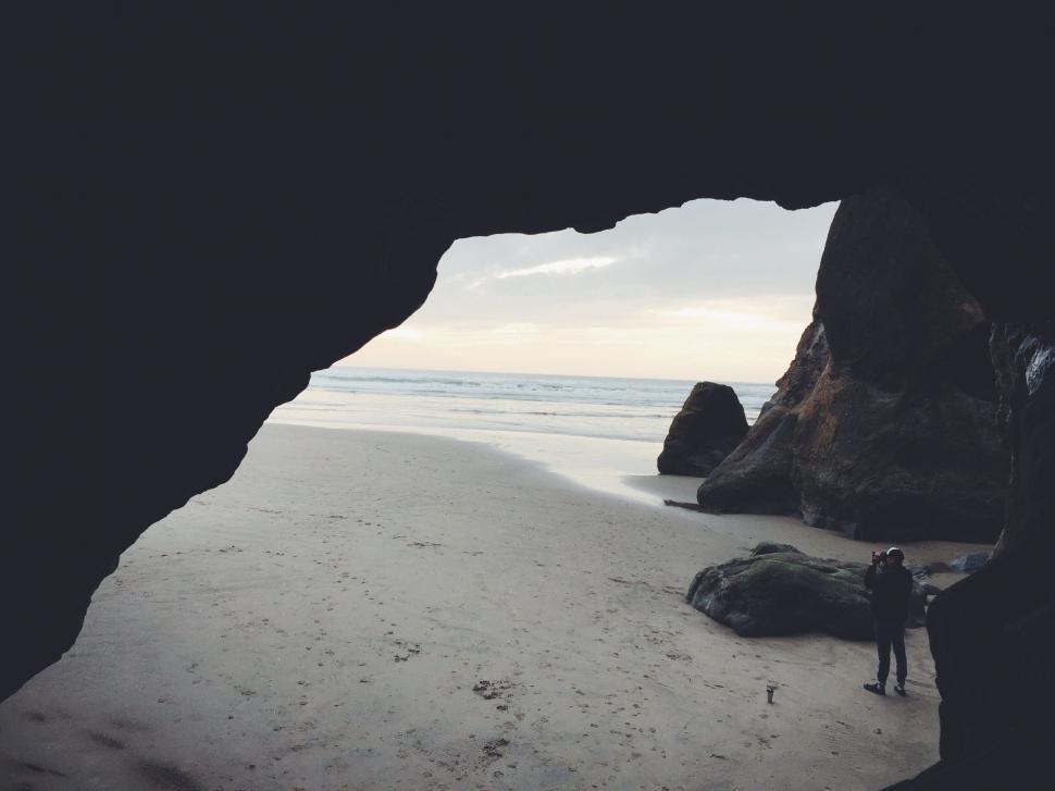 Free Image of Man Standing Next to Cave on Beach 