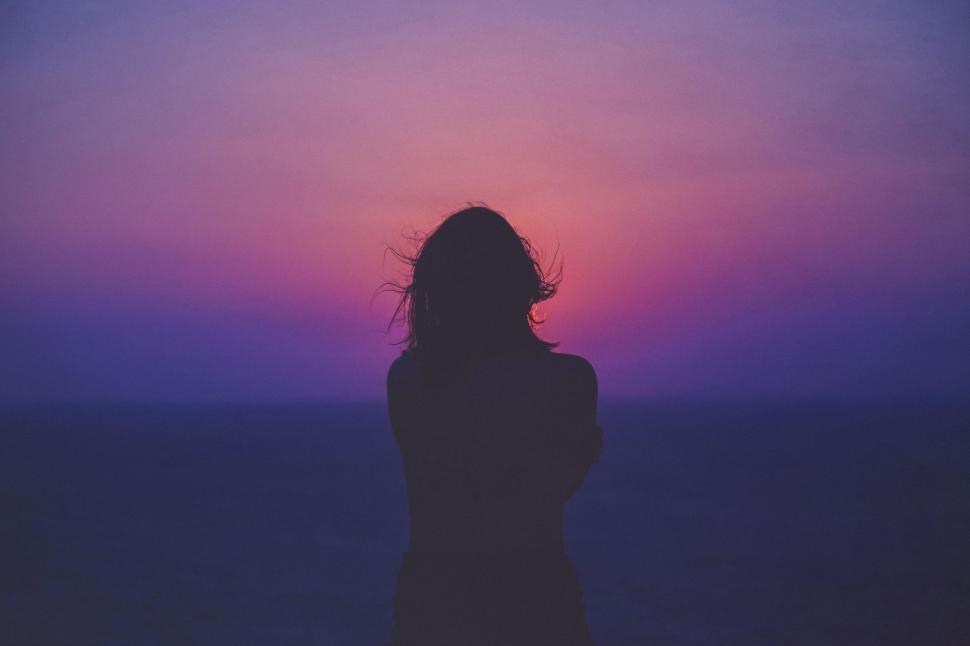 Free Image of Woman Silhouette Standing in Front of Sunset 