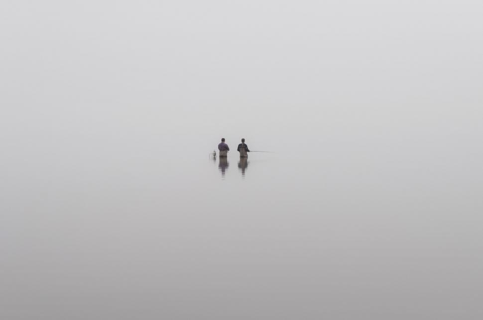Free Image of Two People Standing in the Fog on a Beach 