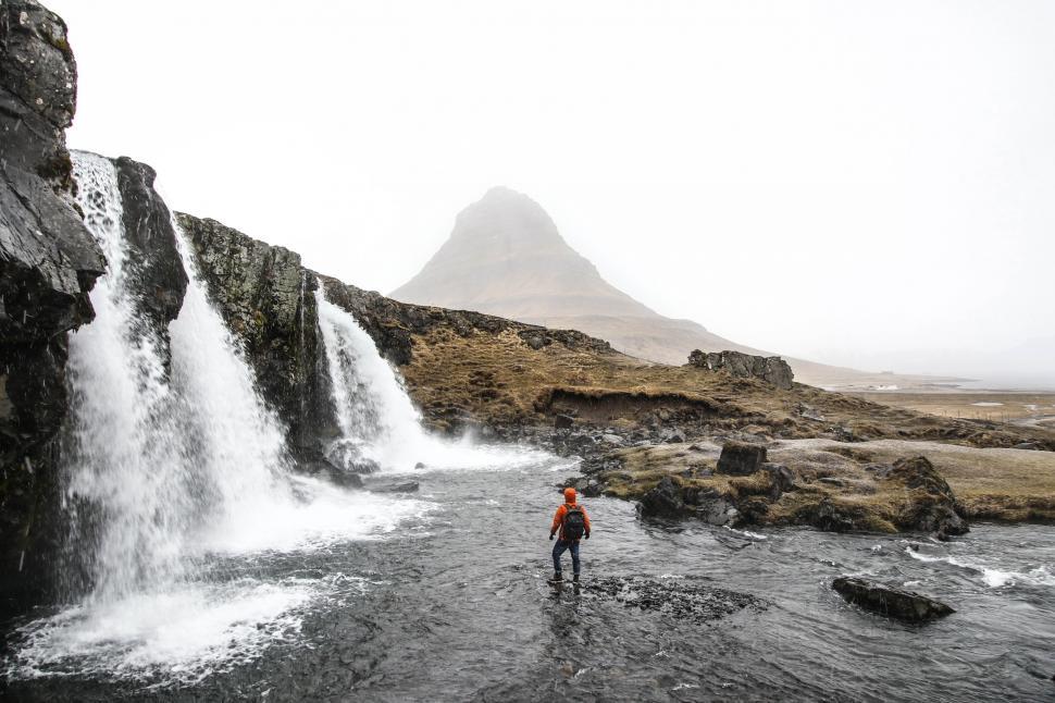 Free Image of Man Standing in River Next to Waterfall 