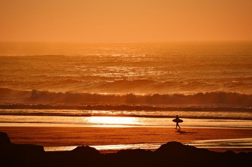 Free Image of Person Carrying Surfboard on Beach at Sunset 