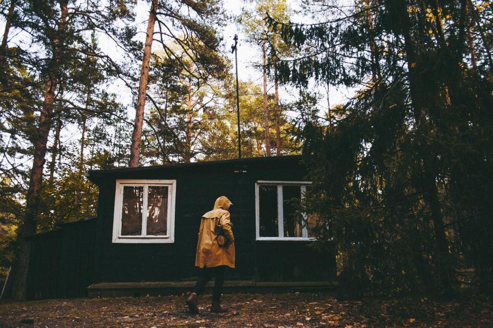 Free Image of Person Standing in Front of Black Cabin in the Woods 