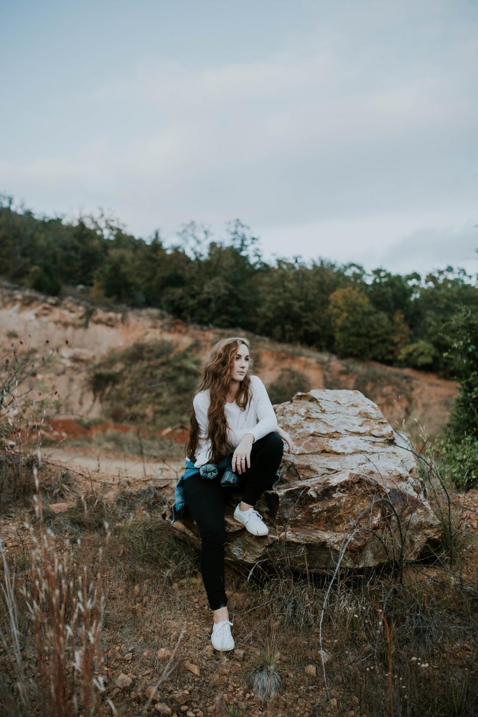 Free Image of Woman Sitting on Rock in Field 